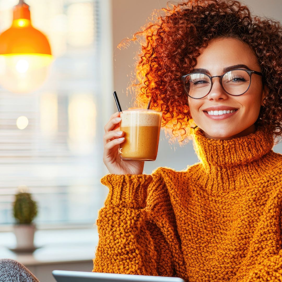 Smiling woman holding a warm drink, looking content after making positive lifestyle changes.